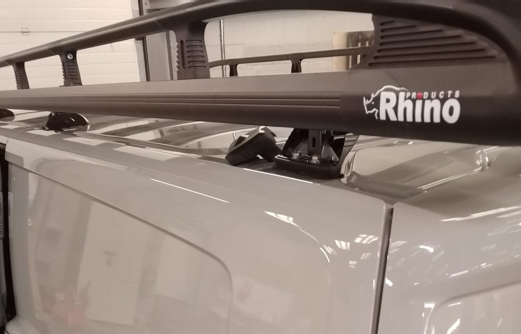Side rails attached to roof bars with Rhino logo visible